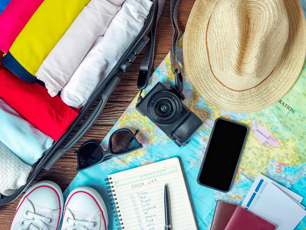 travel items check list camera shoes hat sunglasses and map are displayed on a table
